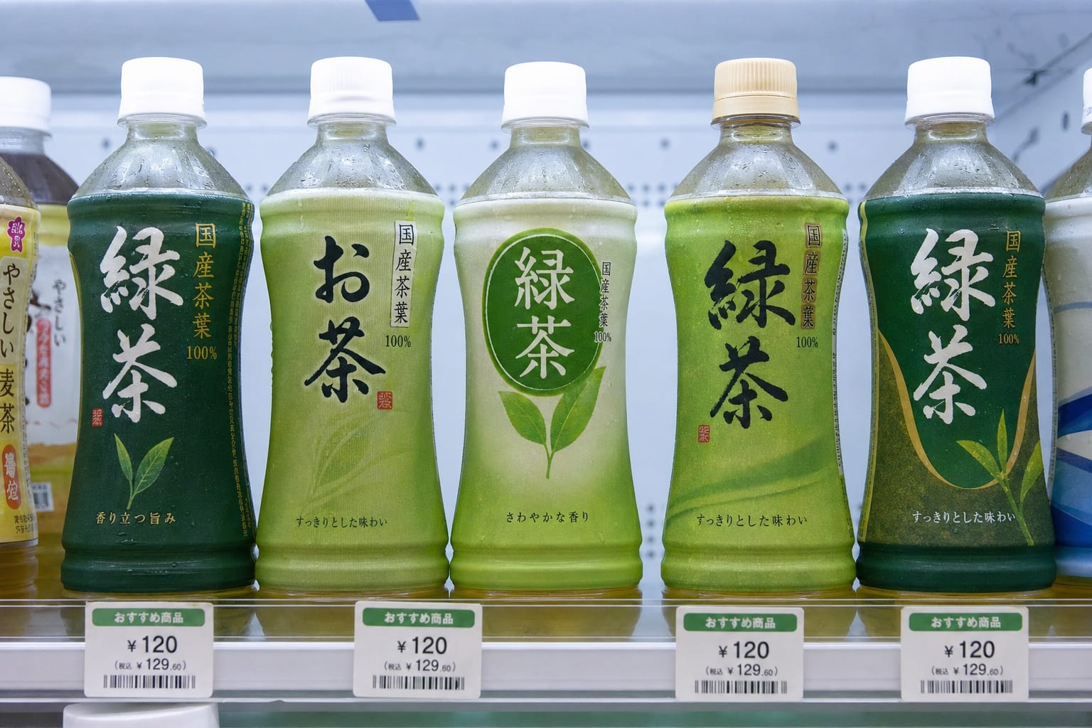 Four brands of bottled green tea lined up in a Japanese convenience store fridge